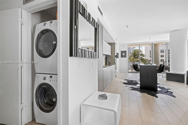 laundry room with light wood-type flooring and stacked washer and dryer