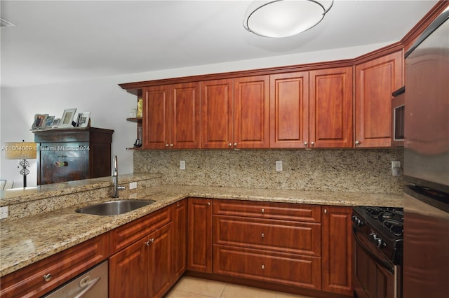 kitchen with light stone counters, light tile patterned floors, sink, tasteful backsplash, and stainless steel appliances