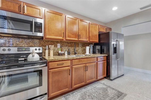 kitchen with light stone countertops, stainless steel appliances, sink, and tasteful backsplash