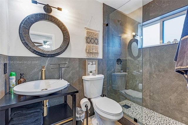 bathroom featuring a tile shower, sink, tile walls, and toilet