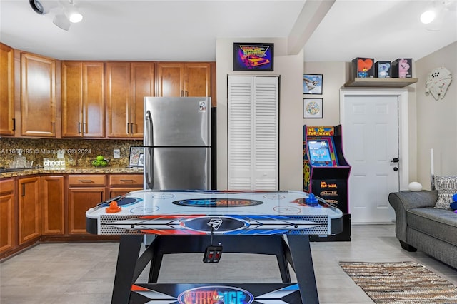 kitchen featuring stainless steel fridge, dark stone countertops, decorative backsplash, and ceiling fan