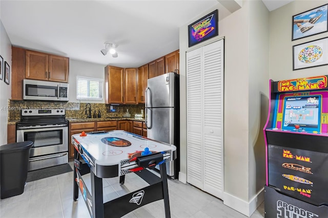 kitchen with stainless steel appliances, backsplash, light tile patterned floors, and sink