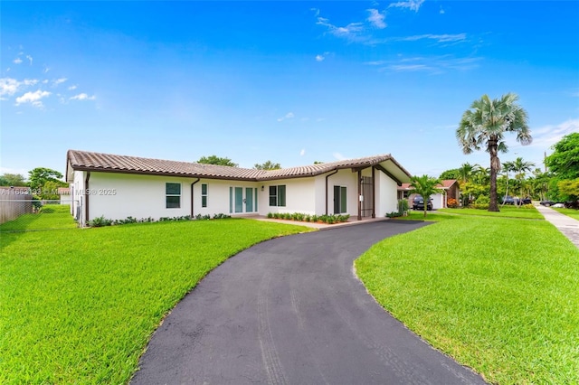 ranch-style home with a front lawn, a tile roof, and stucco siding