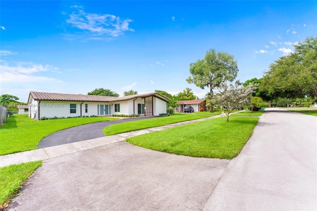 ranch-style house featuring driveway and a front lawn