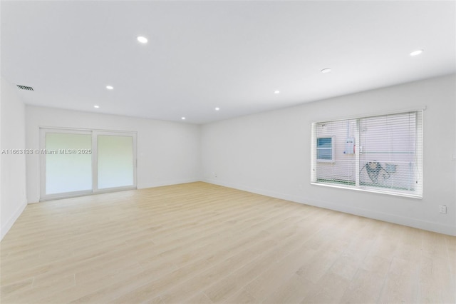 empty room with light wood finished floors, visible vents, baseboards, and recessed lighting