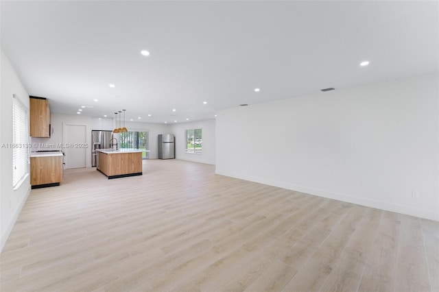 unfurnished living room with light wood-type flooring, visible vents, baseboards, and recessed lighting