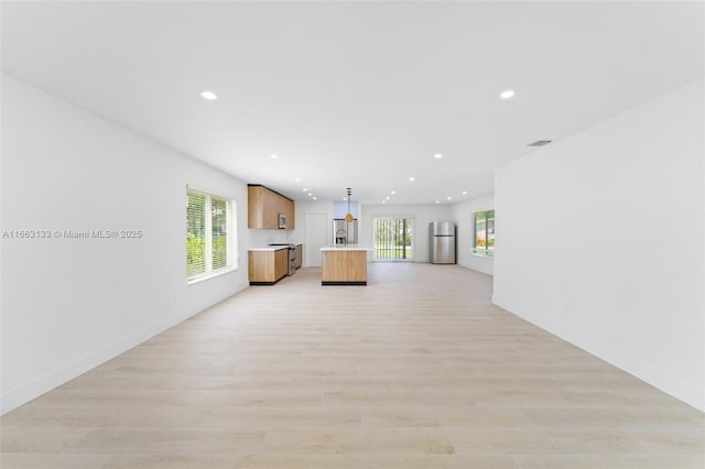 unfurnished living room featuring baseboards, light wood finished floors, a wealth of natural light, and recessed lighting