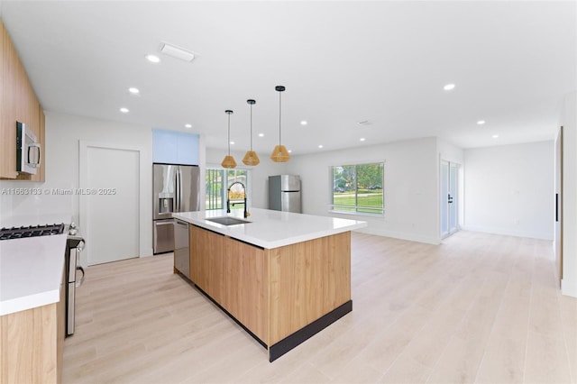 kitchen with a kitchen island with sink, stainless steel appliances, a sink, light countertops, and modern cabinets