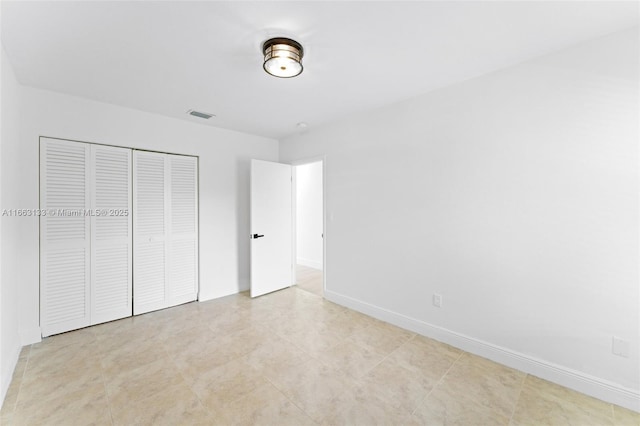 unfurnished bedroom with a closet, visible vents, and baseboards