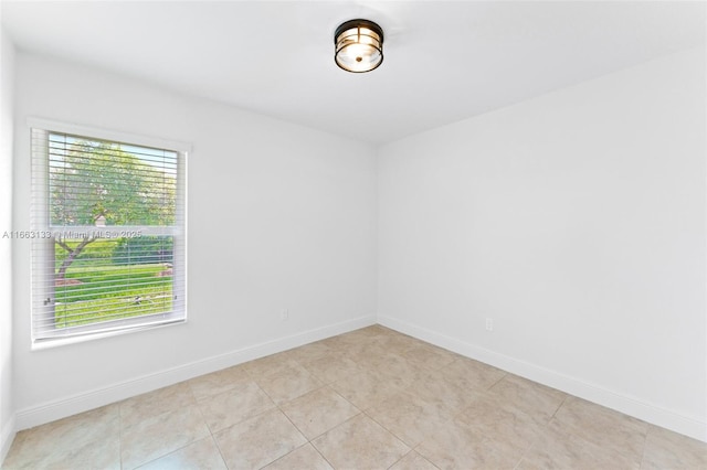 spare room with baseboards and light tile patterned flooring