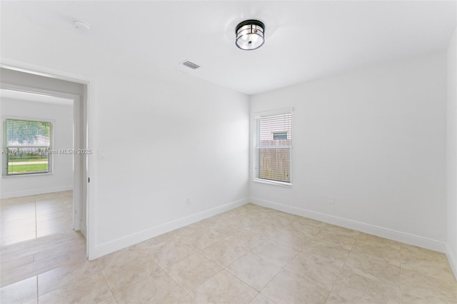 spare room with a healthy amount of sunlight, baseboards, and visible vents