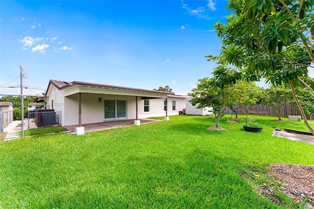 rear view of house featuring stucco siding, a fenced backyard, a lawn, and a patio