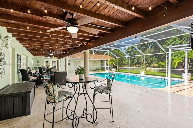 view of swimming pool with ceiling fan, a patio, and a lanai