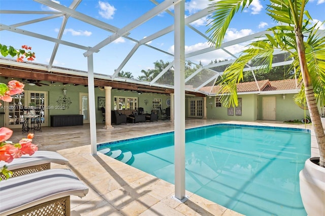 view of pool with glass enclosure, a patio, ceiling fan, and french doors