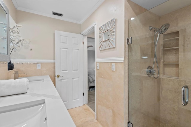 bathroom with crown molding, vanity, a shower with shower door, and tile walls