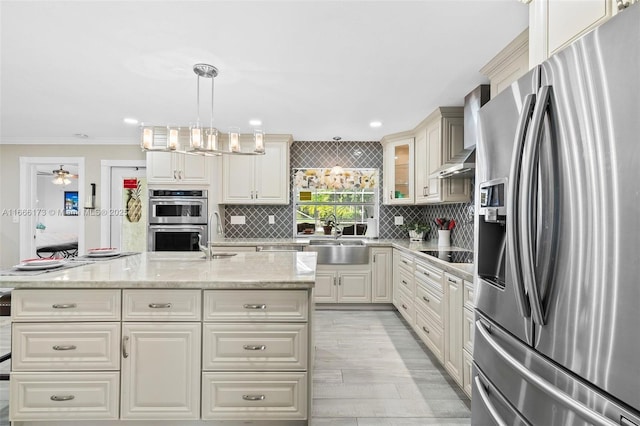 kitchen featuring decorative light fixtures, sink, backsplash, light stone counters, and stainless steel appliances