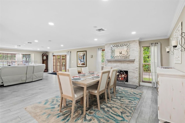 dining space with light hardwood / wood-style floors, ornamental molding, and a healthy amount of sunlight