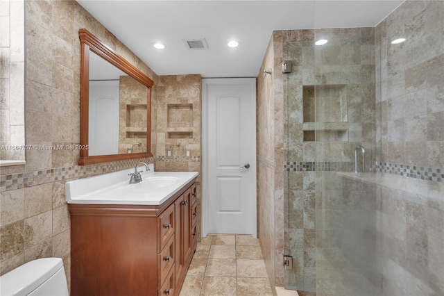 bathroom featuring an enclosed shower, vanity, toilet, and tile walls