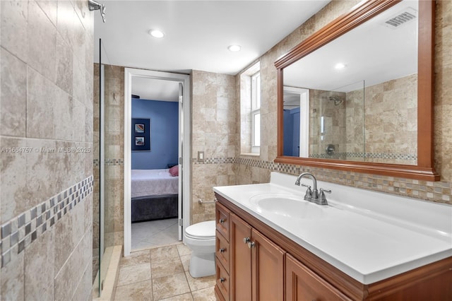 bathroom featuring tile patterned floors, vanity, a shower, tile walls, and toilet