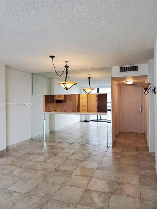 kitchen with a textured ceiling, kitchen peninsula, and decorative light fixtures