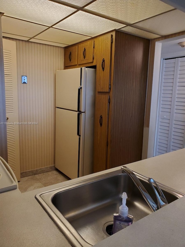 kitchen with light tile patterned flooring, sink, and white fridge