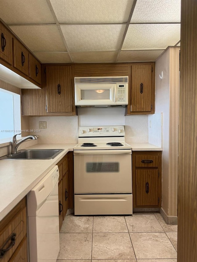 kitchen featuring a drop ceiling, white appliances, light tile patterned flooring, and sink