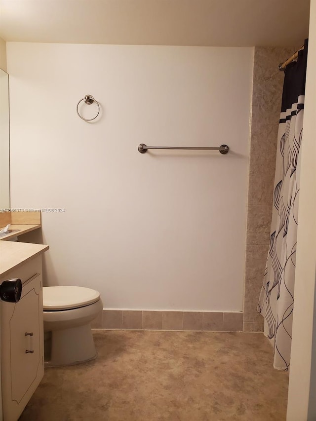 bathroom with curtained shower, vanity, and toilet