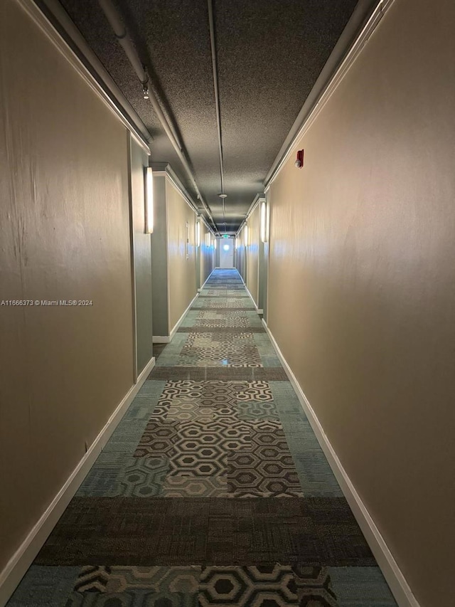 corridor featuring carpet, a textured ceiling, and crown molding