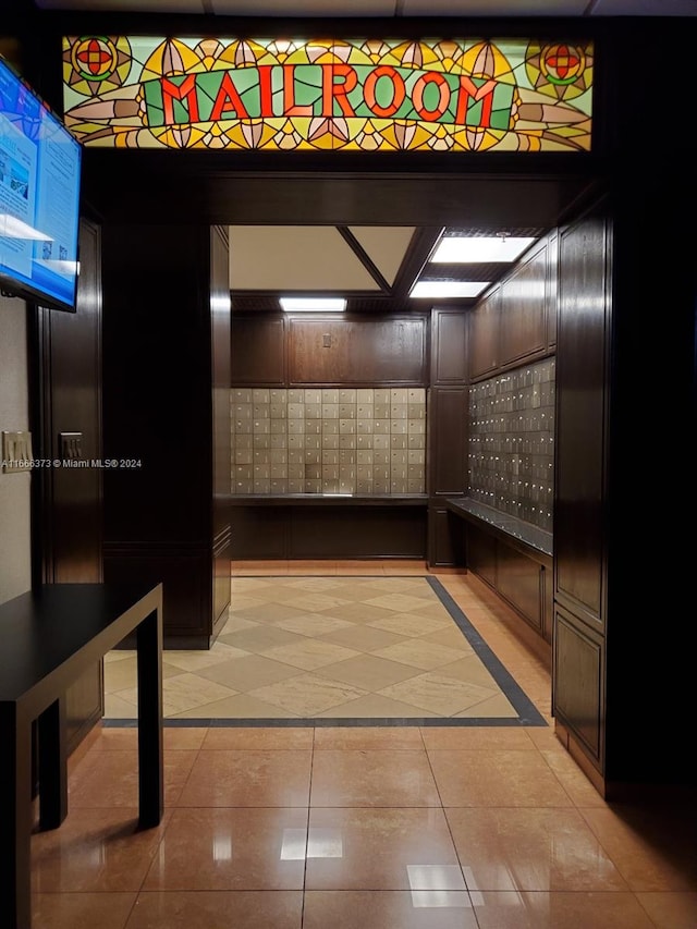 corridor with light tile patterned floors and a paneled ceiling