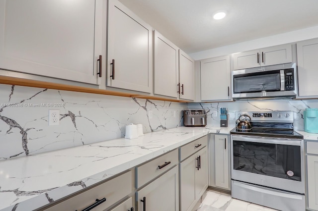 kitchen with backsplash, stainless steel appliances, and light stone counters