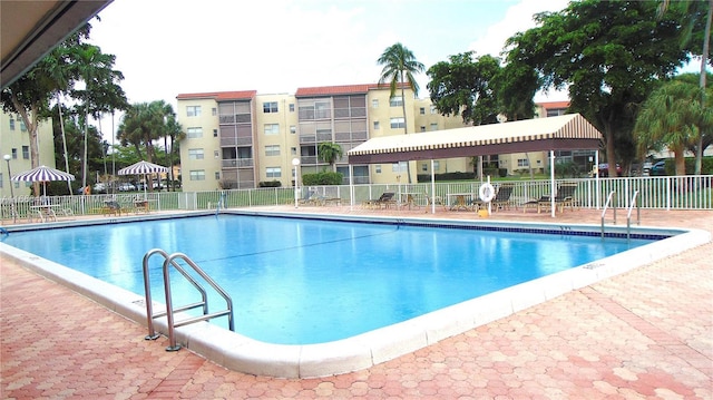 community pool with a patio area and fence