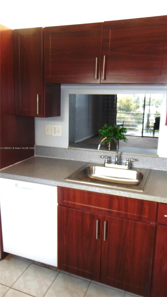 kitchen featuring light tile patterned floors, a sink, and reddish brown cabinets