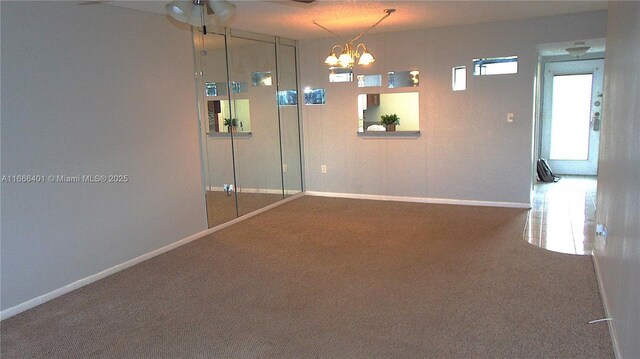 carpeted spare room featuring ceiling fan with notable chandelier