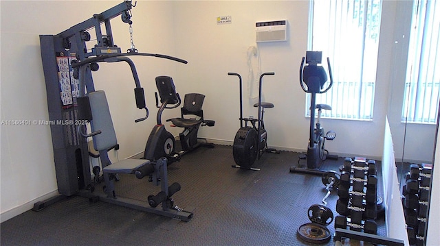 exercise room with baseboards and a wall unit AC