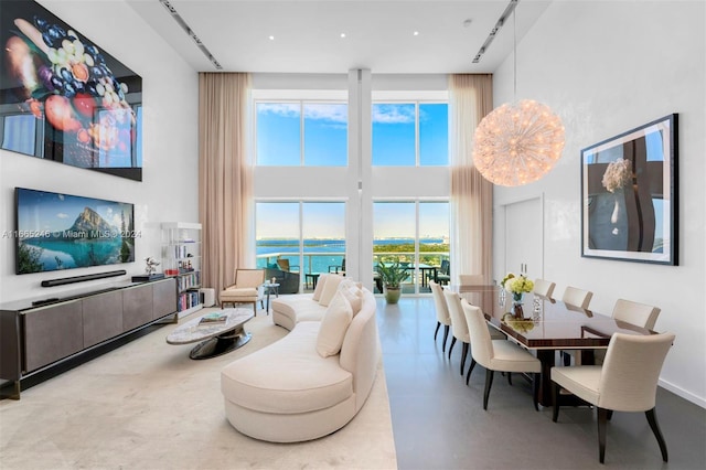 living room featuring concrete floors, a water view, and a high ceiling