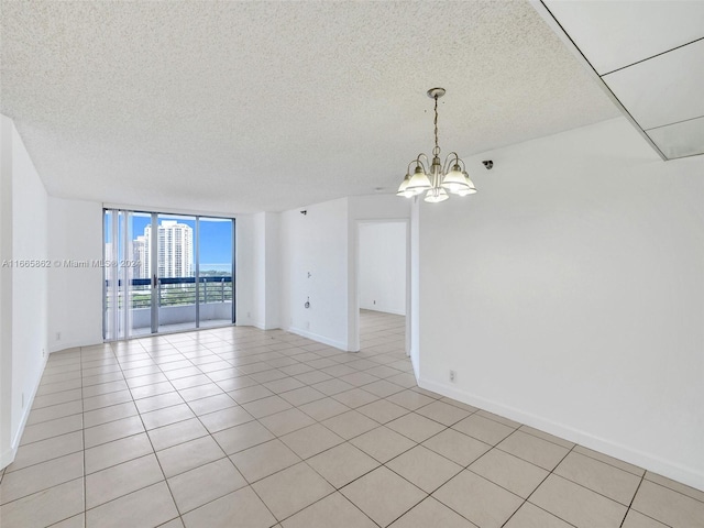 tiled spare room with floor to ceiling windows, a chandelier, and a textured ceiling