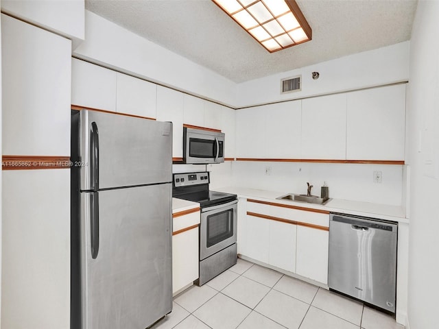 kitchen with stainless steel appliances, white cabinets, a textured ceiling, and sink