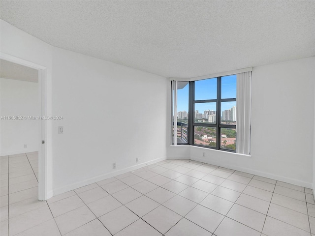 spare room with a textured ceiling and light tile patterned flooring