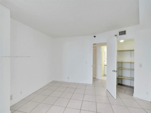 tiled empty room featuring a textured ceiling