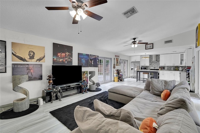 living room with a textured ceiling, ceiling fan, and vaulted ceiling