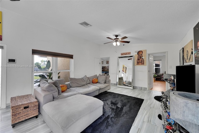 living room featuring ceiling fan, a textured ceiling, and vaulted ceiling