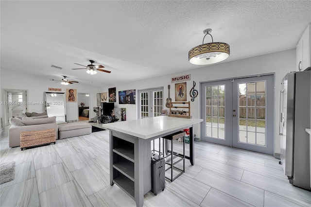 kitchen with ceiling fan, french doors, a kitchen breakfast bar, decorative light fixtures, and white cabinets