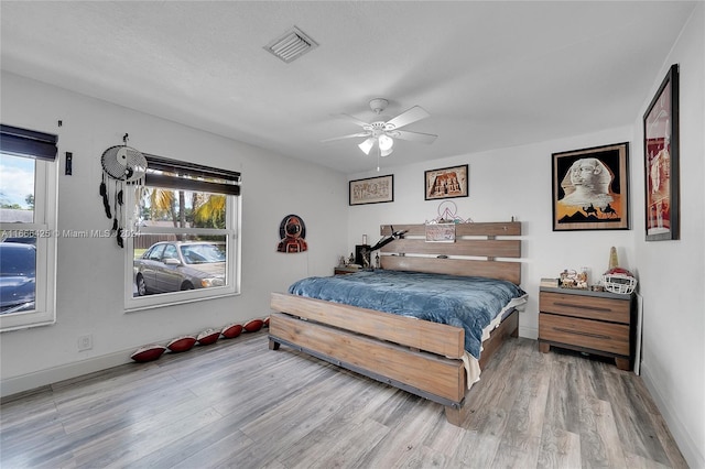 bedroom with ceiling fan, hardwood / wood-style floors, and a textured ceiling