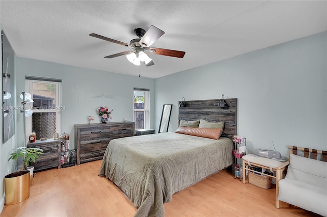 bedroom with ceiling fan, wood-type flooring, and multiple windows