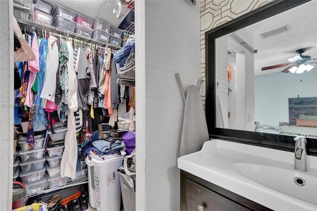 bathroom with vanity, ceiling fan, and a textured ceiling