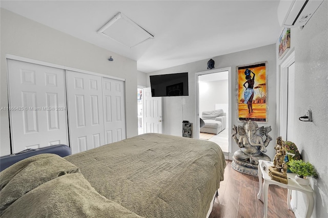 bedroom featuring an AC wall unit, a closet, and hardwood / wood-style flooring