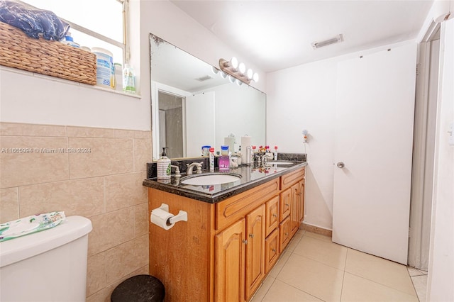 bathroom with tile patterned floors, vanity, toilet, and tile walls