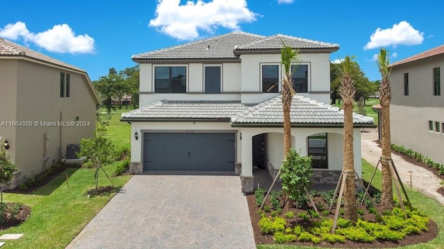 mediterranean / spanish-style home featuring a garage, cooling unit, and a front lawn