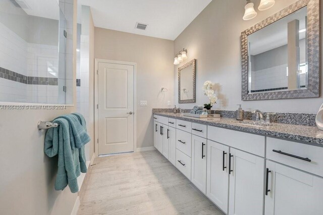 bathroom featuring vanity, hardwood / wood-style flooring, and tiled shower