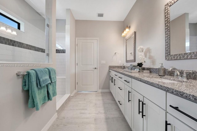 bathroom featuring vanity, wood-type flooring, and tiled shower